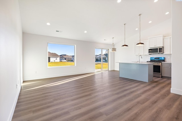 kitchen featuring a center island with sink, appliances with stainless steel finishes, open floor plan, decorative light fixtures, and light countertops