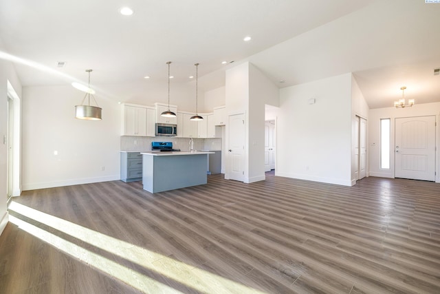 kitchen featuring pendant lighting, light countertops, stainless steel microwave, a kitchen island with sink, and white cabinetry