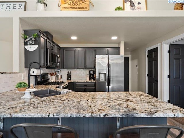 4210 Campolina Ln, Pasco, WA 99301 - kitchen featuring stainless steel appliances, light stone counters, a peninsula, tasteful backsplash, and recessed lighting