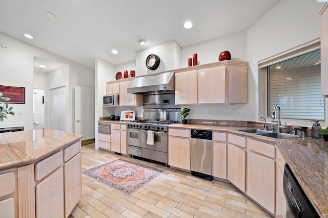 kitchen with appliances with stainless steel finishes, sink, light brown cabinets, wall chimney range hood, and light wood-type flooring