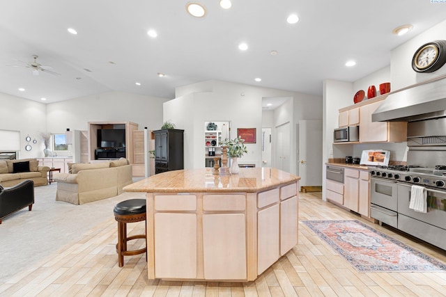 kitchen featuring a kitchen island, appliances with stainless steel finishes, lofted ceiling, a kitchen breakfast bar, and light hardwood / wood-style floors