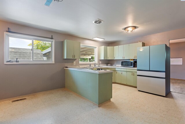 1506 Wilson St, Richland, WA 99354 - kitchen featuring stainless steel microwave, freestanding refrigerator, light flooring, a peninsula, and light countertops
