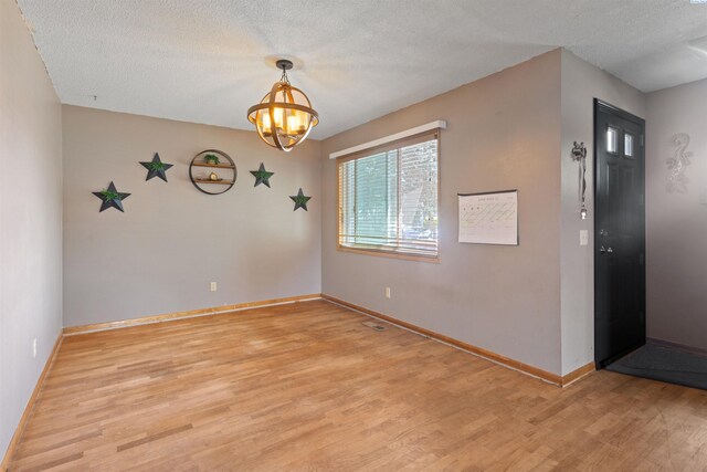 1506 Wilson St, Richland, WA 99354 - empty room featuring light wood finished floors, a chandelier, and a textured ceiling