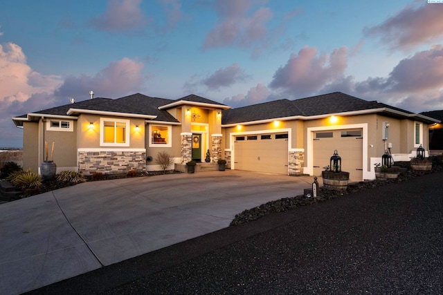 prairie-style house with a garage, stone siding, concrete driveway, and stucco siding