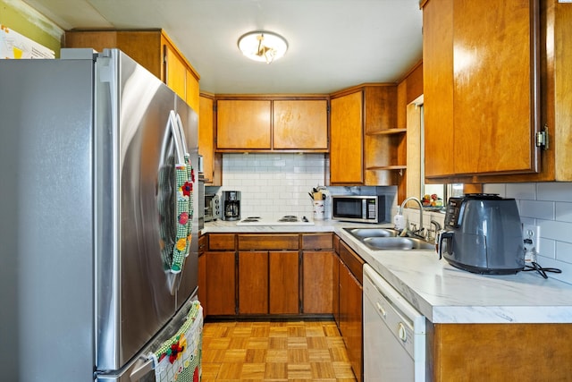 kitchen with sink, decorative backsplash, stainless steel appliances, and light parquet flooring