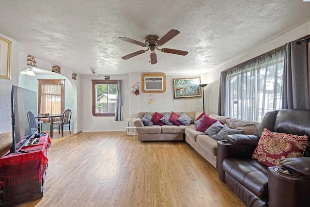 living room with light hardwood / wood-style flooring, an AC wall unit, and a textured ceiling