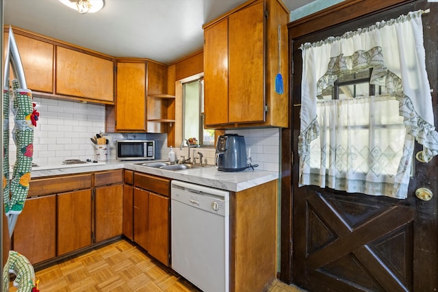 kitchen with light parquet floors, dishwasher, sink, and decorative backsplash