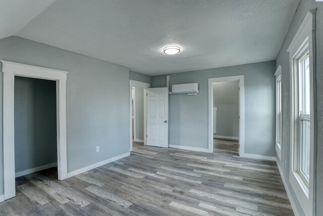 503 Grandridge Ave, Grandview, WA 98930 - unfurnished bedroom featuring baseboards, a textured ceiling, wood finished floors, and a wall mounted air conditioner