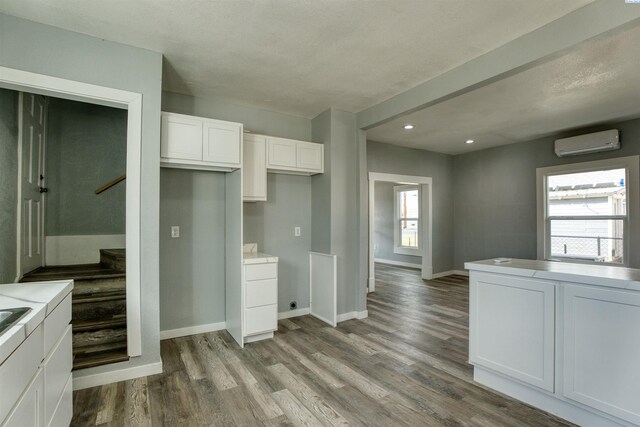 503 Grandridge Ave, Grandview, WA 98930 - kitchen featuring white cabinets, baseboards, a wall unit AC, and wood finished floors