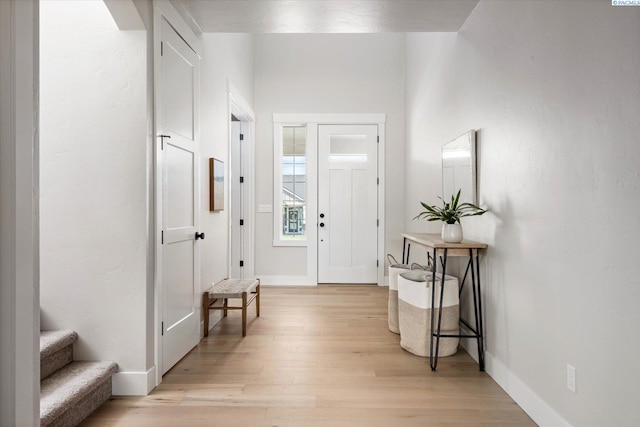 entryway with light wood-style floors, baseboards, and stairs