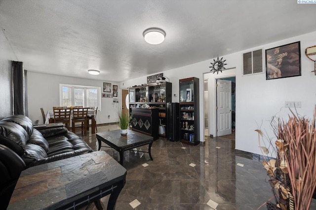 living room with marble finish floor, visible vents, a textured ceiling, and baseboards