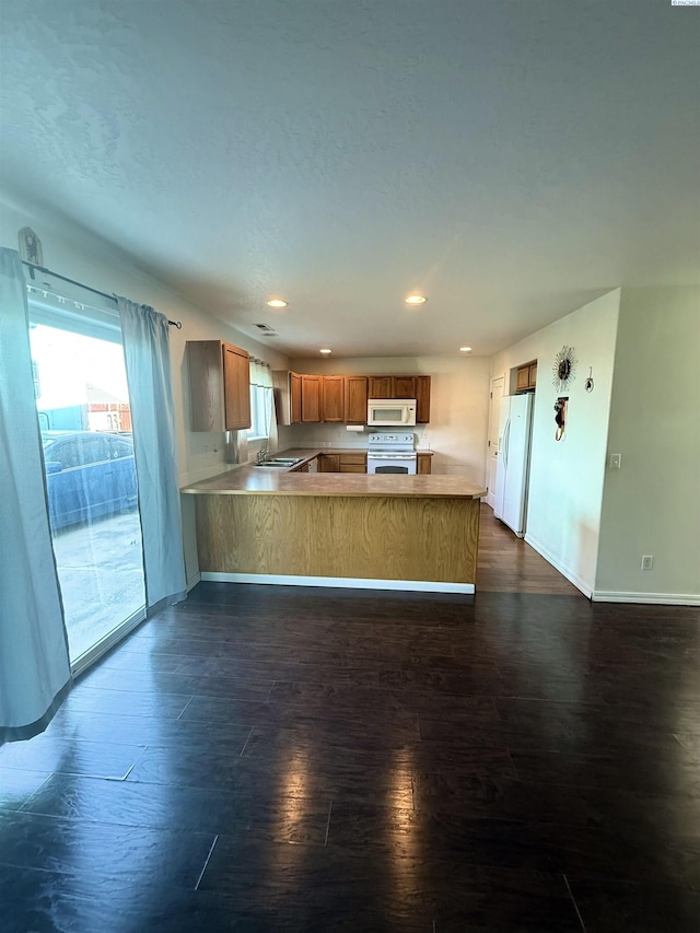 808 N Owen Ave, Pasco, WA 99301 - kitchen with white appliances, a peninsula, dark wood finished floors, brown cabinetry, and plenty of natural light