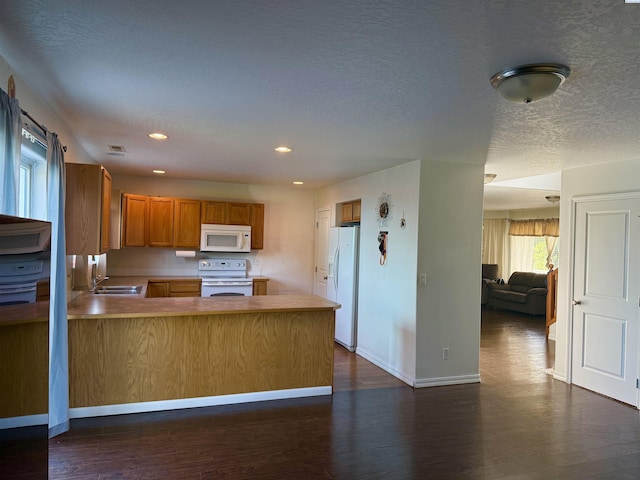 808 N Owen Ave, Pasco, WA 99301 - kitchen featuring white appliances, brown cabinetry, a peninsula, dark wood-type flooring, and a sink