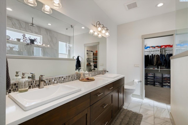 3905 Orchard St, West Richland, WA 99353 - bathroom featuring a walk in closet, double vanity, toilet, marble look tiles, and recessed lighting