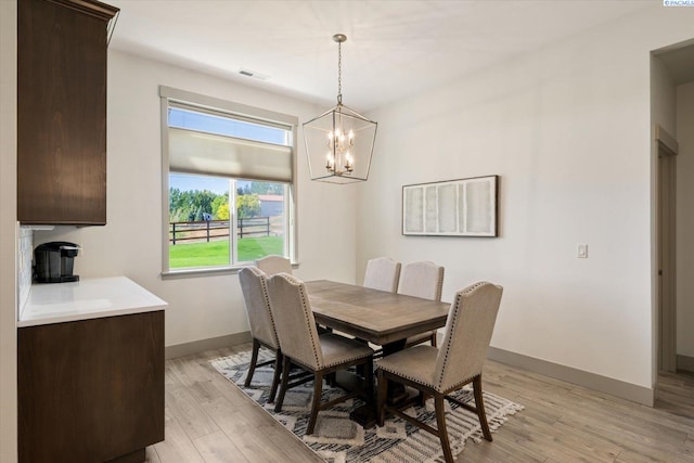 3905 Orchard St, West Richland, WA 99353 - dining area featuring a chandelier, light wood-style flooring, and baseboards