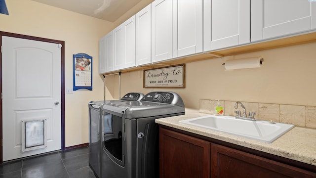 laundry area with dark tile patterned flooring, cabinet space, separate washer and dryer, and a sink