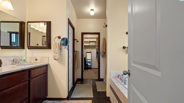 bathroom with tiled bath, tile patterned flooring, and vanity