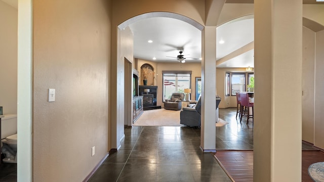 hallway with recessed lighting, baseboards, and arched walkways