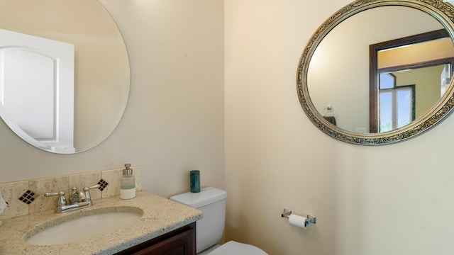 bathroom featuring tasteful backsplash, toilet, and vanity