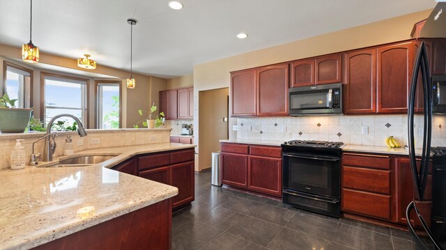 kitchen with a sink, decorative backsplash, black appliances, decorative light fixtures, and light stone counters