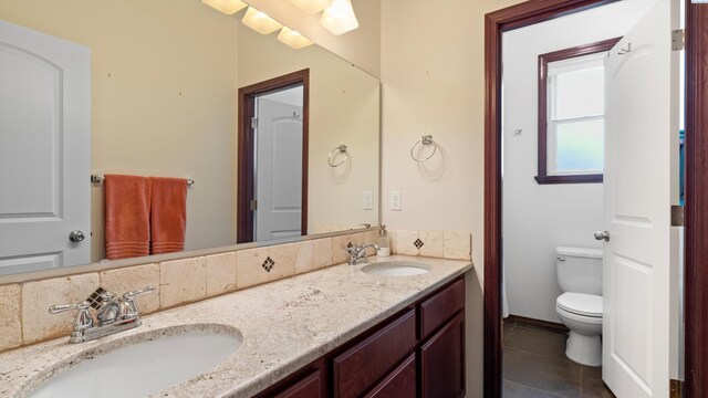 bathroom featuring double vanity, toilet, tile patterned flooring, and a sink
