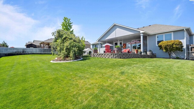 rear view of property featuring a lawn and fence