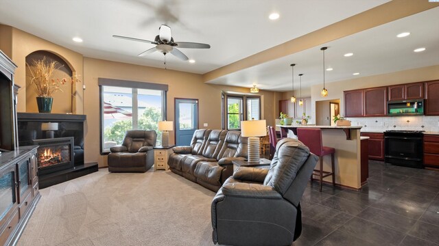 living area featuring recessed lighting, a ceiling fan, and a warm lit fireplace