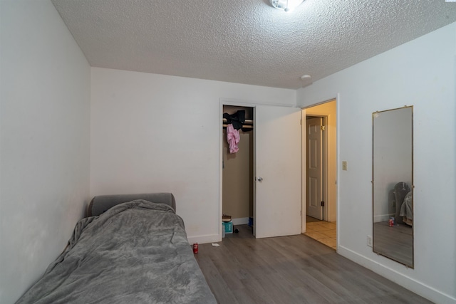775 S 4th Ave, Othello, WA 99344 - bedroom with wood finished floors, a textured ceiling, a closet, and baseboards