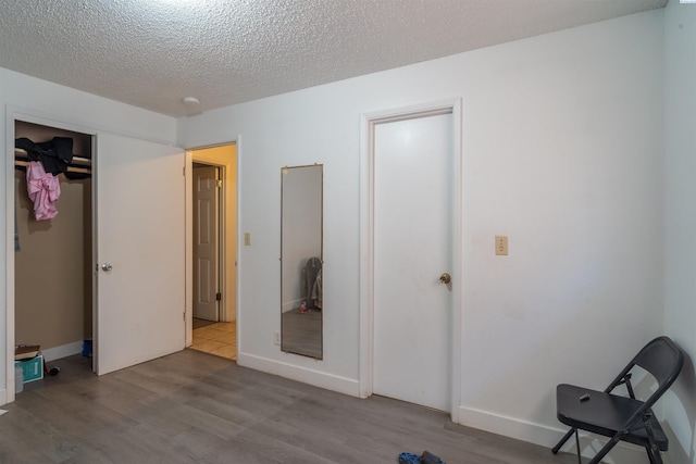 775 S 4th Ave, Othello, WA 99344 - unfurnished bedroom with wood finished floors, a textured ceiling, baseboards, and a closet