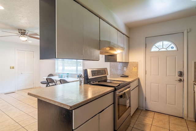 775 S 4th Ave, Othello, WA 99344 - kitchen with electric stove, under cabinet range hood, light tile patterned flooring, plenty of natural light, and recessed lighting
