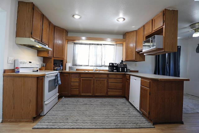 313 E 5th Ave, Kennewick, WA 99336 - kitchen with white appliances, under cabinet range hood, brown cabinets, and light wood-style floors