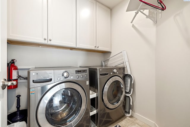 laundry area featuring washer and dryer, tile patterned flooring, cabinet space, and baseboards