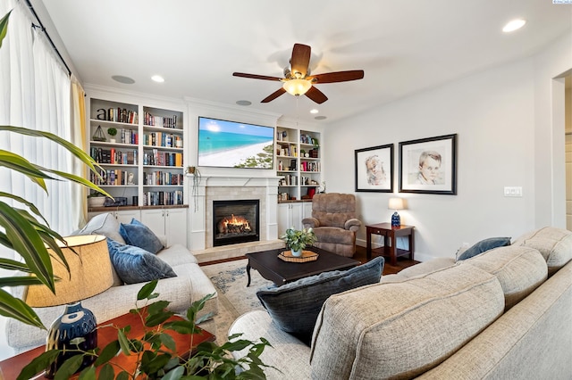 living room with ceiling fan, built in shelves, a tiled fireplace, and recessed lighting