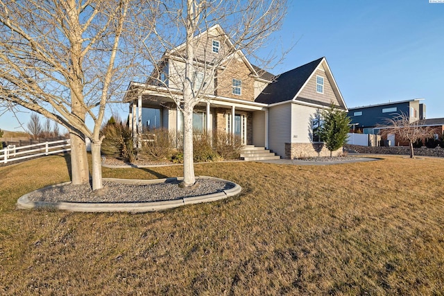 view of front of property with stone siding, fence, and a front yard