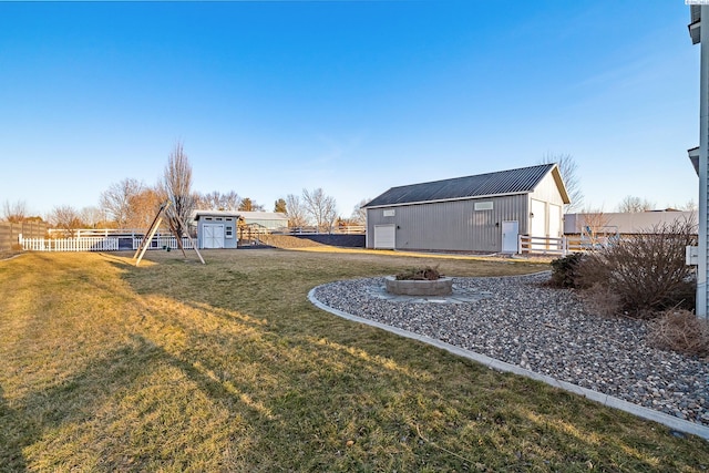 view of yard with fence, an outbuilding, a playground, and an outdoor structure