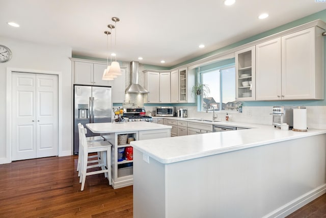 kitchen featuring dark wood-style flooring, stainless steel appliances, light countertops, glass insert cabinets, and wall chimney exhaust hood