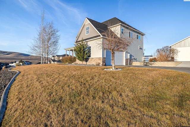 view of front of house featuring driveway, stone siding, and a front lawn