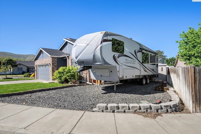 521 Eastgate Dr, Prosser, WA 99350 - view of side of property featuring fence, an attached garage, brick siding, and a mountain view