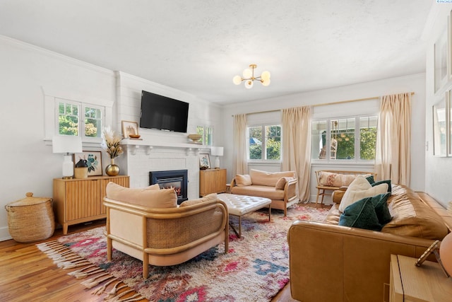 living room featuring hardwood / wood-style flooring, a fireplace, crown molding, and a chandelier