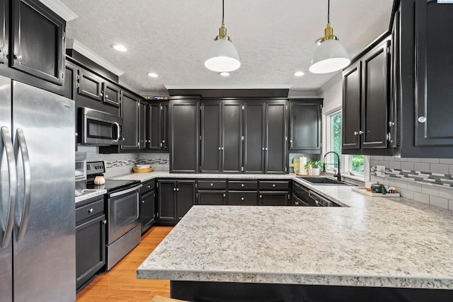 kitchen with pendant lighting, sink, light hardwood / wood-style flooring, stainless steel appliances, and ornamental molding