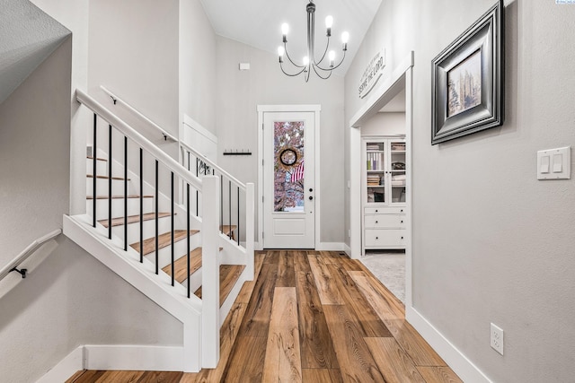 entrance foyer with hardwood / wood-style flooring, a high ceiling, and an inviting chandelier