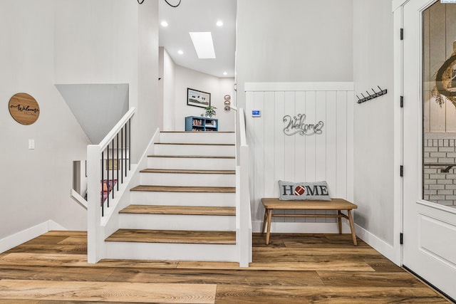 stairs with hardwood / wood-style floors and a skylight