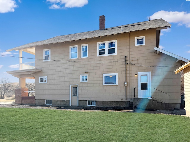 rear view of house featuring a balcony and a lawn