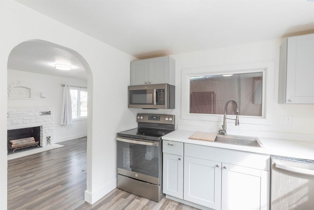 615 SW Winter Cir, Pullman, WA 99163 - kitchen featuring appliances with stainless steel finishes, a sink, arched walkways, baseboards, and light wood-style floors