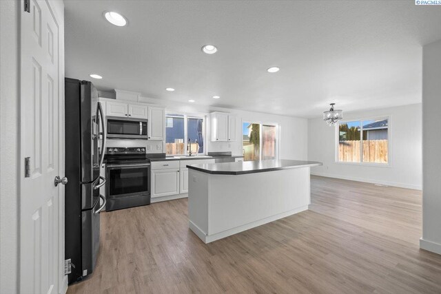 kitchen with appliances with stainless steel finishes, light hardwood / wood-style floors, sink, and white cabinets