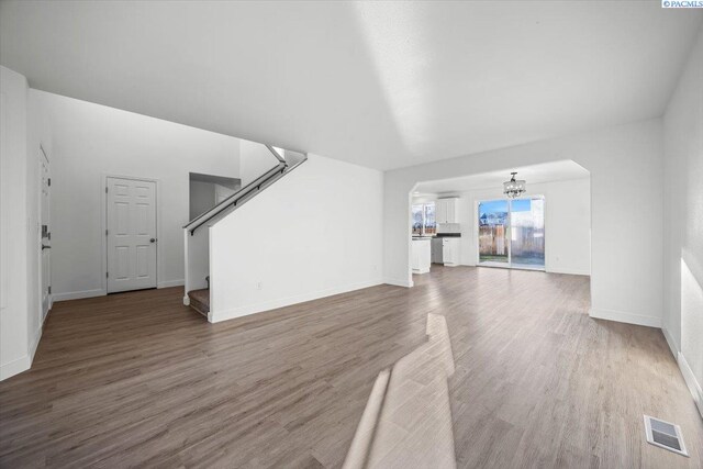 unfurnished living room with an inviting chandelier and dark wood-type flooring