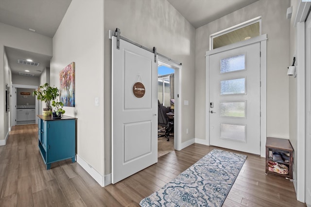 entryway featuring a barn door, wood finished floors, a high ceiling, and baseboards