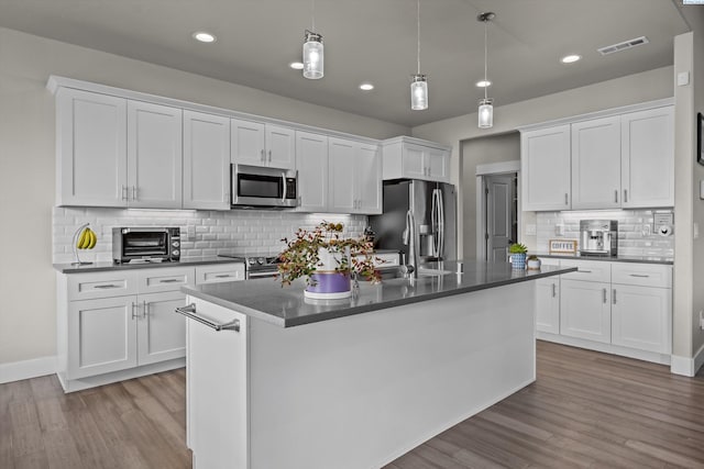 kitchen featuring appliances with stainless steel finishes, dark countertops, decorative backsplash, white cabinetry, and recessed lighting