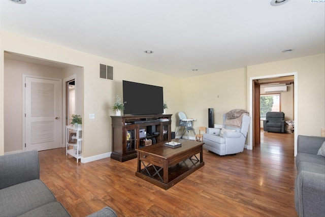 living room with dark hardwood / wood-style floors and an AC wall unit