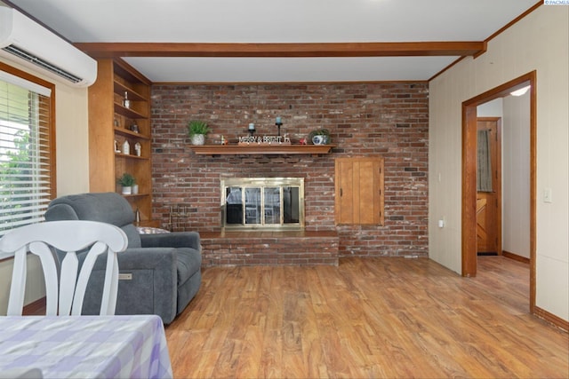 living room featuring light hardwood / wood-style flooring, a wall unit AC, a fireplace, built in shelves, and beamed ceiling